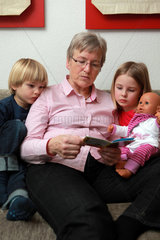 Handewitt  Deutschland  eine Grossmuttern liest ihren beiden Enkeln aus einem Pixi-Buch vor