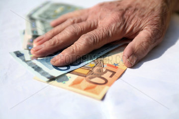 Berlin  Deutschland  die Haende einer Rentnerin liegen auf Geldscheinen
