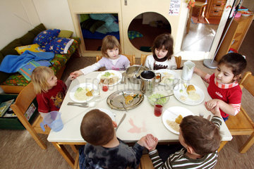 Berlin  Kinder sitzen gemeinsam am Tisch und essen zu Mittag