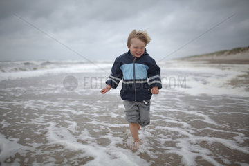 Hvide Sande  Daenemark  ein Junge rennt barfuss am Strand