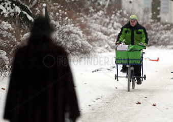 Berlin  Deutschland  Postbote der PIN AG faehrt auf seinem Fahrrad einen schneebedeckten Gehweg entlang