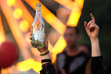 Chemnitz  Deutschland  ein Jugendlicher hebt eine leere Flasche Alkohol waehrend eines Volksfestes in die Luft