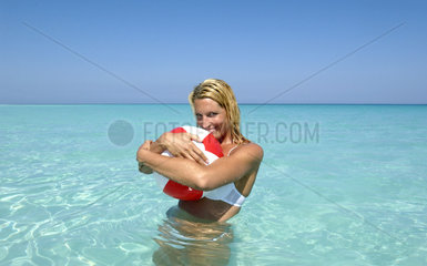 Junge Frau umarmt einen Wasserball  Bahamas