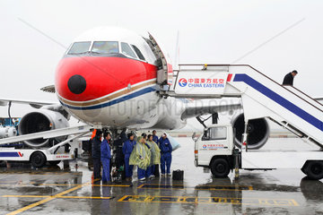 Shanghai  Flughafenpersonal sucht bei Regen Schutz unter einer Maschine der China Eastern auf dem Rollfeld des Flughafen Pudong
