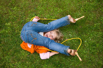 Berlin  Maedchen spielt mit einem Springseil auf dem Rasen