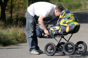 Stuttgart  Deutschland  Mann spielt mit Baby im Kinderwagen