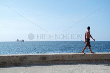 Havanna  Kuba  ein Mann geht auf der Steinmauer des Malecon entlang