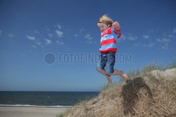 Hvide Sande  Daenemark  ein Junge springt von einer Duene