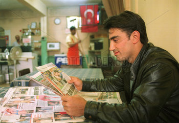 Mann in einem Cafe liest eine Tageszeitung (Tuerkei)