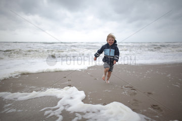 Hvide Sande  Daenemark  ein Junge rennt barfuss am Strand