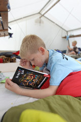 Ploen  Deutschland  ein Junge liegt im Grossraumzelt und liest ein Buch