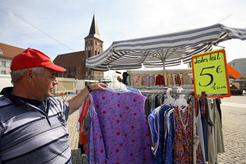 Haendler sortiert seine Kleider auf dem Marktplatz von Pasewalk