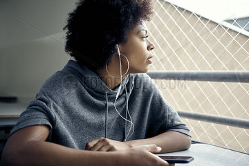 Young woman listening to earphones and gazing out window