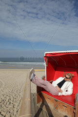 Rantum  Deutschland  eine Frau entspannt in einem Strandkorb am Strand auf Sylt