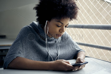 Young woman looking at smartphone and listening to earphones