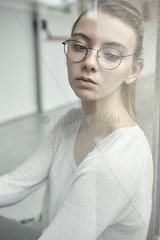 Young woman looking through window in thought  portrait