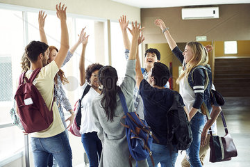 Group of students standing in a circle with hands raised in the air