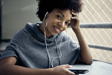 Young woman using smartphone and earphones  smiling  portrait