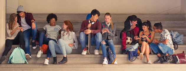 Students chatting together and looking at smartphones between classes