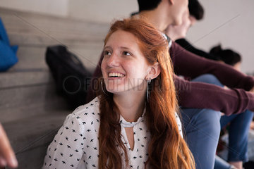Young woman chatting with friend and smiling cheerfully]