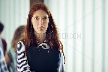 Young woman sticking out tongue in corridor