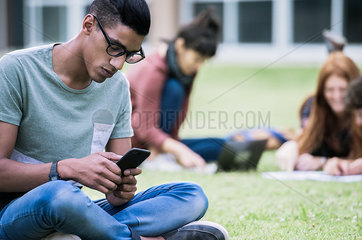 Male college student using smartphone outdoors