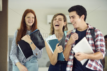 Classmates laughing together while walking in school corridor
