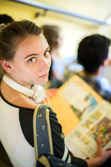 Female student holding book on lap  looking over shoulder at camera