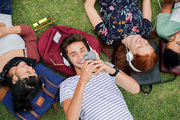 Group of college students relaxing together on grass between classes