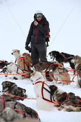 Saelen  Schweden  Mann steht zwischen eingespannten Siberian Huskies