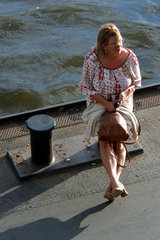 Hamburg  eine Frau sitzt wartend auf einem Poller