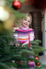 Harrislee  Deutschland  ein Maedchen dekoriert einen Weihnachtsbaum
