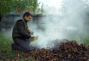 Mann verbrennt Laub in seinem Garten  Polen