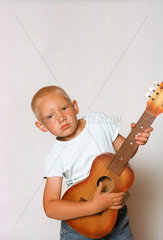fuenfjaehriger Junge spielt Gitarre