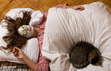 Todtnau  Deutschland  eine Frau liegt mit Gurkenmaske und Katze im Bett