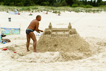 Swinemuende  Polen  ein Mann hat eine Sandburg am Strand gebaut