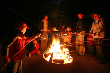 Prangendorf  Menschen grillen Wuerste ueber offenem Feuer