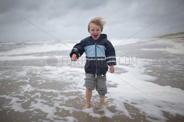 Hvide Sande  Daenemark  ein Junge laeuft barfuss am Strand