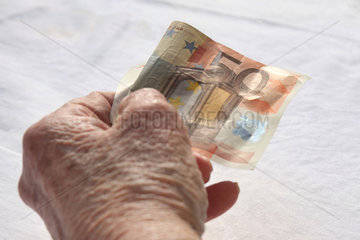 Berlin  Deutschland  die Hand einer Rentnerin mit einem Euroschein