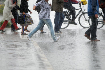 Kiel  Deutschland  Fussgaenger laufen bei starkem Regen ueber eine Strasse