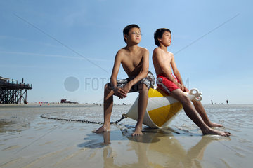 St. Peter-Ording  Deutschland  Kinder sitzen am Strand bei Niedrigwasser auf eine Positionstonne