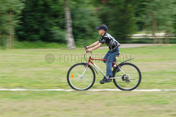 Junge faehrt Rad im Park  Berlin