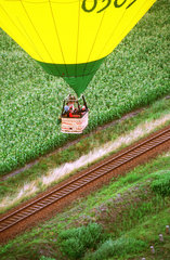 Heissluftballon fliegt ueber Bahnstrecke