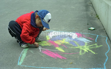 Kind malt mit Kreide auf der Strasse in Poznan
