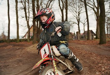 Kleiner Junge faehrt Motorrad im Garten  Norddeutschland