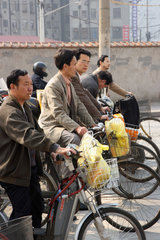 Shanghai  Fahrradfahrer warten an einer Ampel