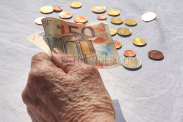 Berlin  Deutschland  die Hand einer Rentnerin mit einem Euroschein und Muenzen