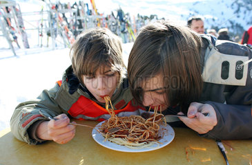 Jerzens  Oesterreich  zwei Kinder essen Spaghetti von einem Teller