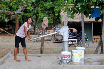 Phum Chikha  Kambodscha  eine junge Frau fuellt Wassereimer am Dorfbrunnen
