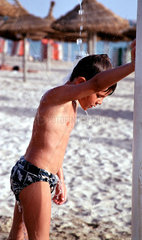 Kind duscht sich am Strand auf Mallorca